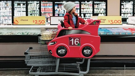 A little boy riding a grocery store cart