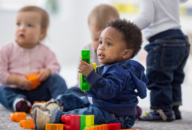 Babies playing with toys indoors at a daycare.