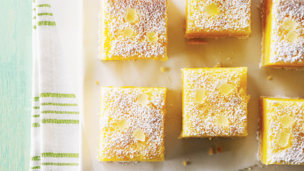 squares of lemon bars on parchment paper with candied lemon on top