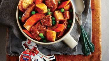 bowl of hearty beef stew with potatoes, carrots and peas