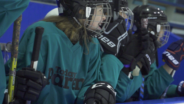 Kids on hockey bench with helmets, jerseys and sticks