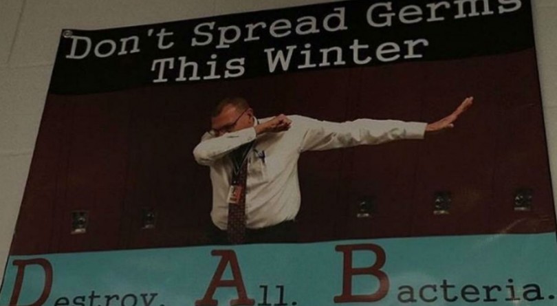Principal dabs in poster to demonstrate what you should do if you cough or sneeze
