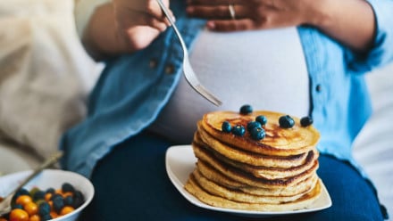 A pregnant woman eating pancakes, a sign she is a having a girl