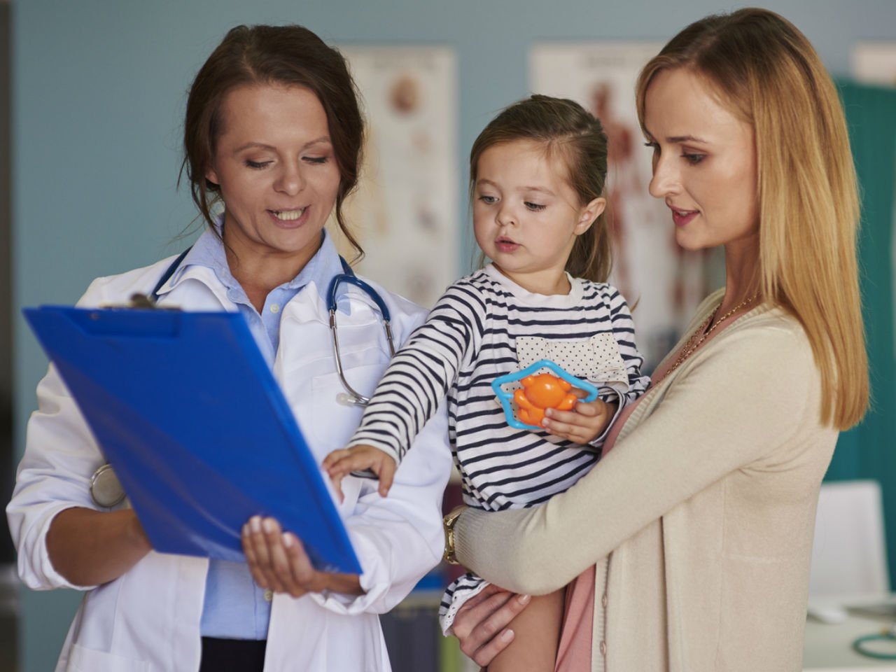 Doctor, mom and young child look onto the doctors notes in the ER