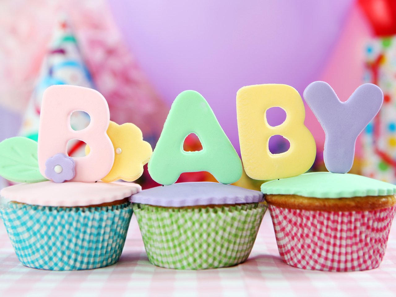 the word Baby spelled out on top of cupcakes