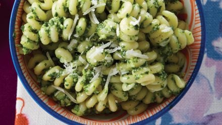 A bowl of pasta with green pesto on it