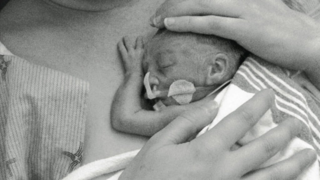 Close up of mom holding baby in the NICU providing skin to skin contact