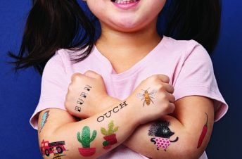A little girl with her arms folded showing off tattoos