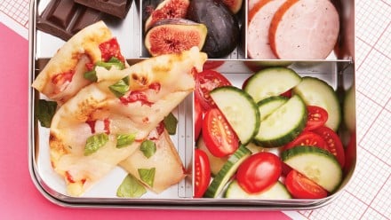 bento box with pizza, fig, chocolate, veggies and fruit