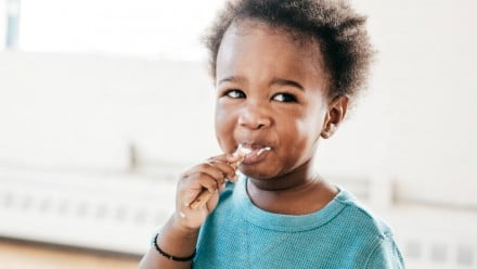 A little girl eating something with a spoon
