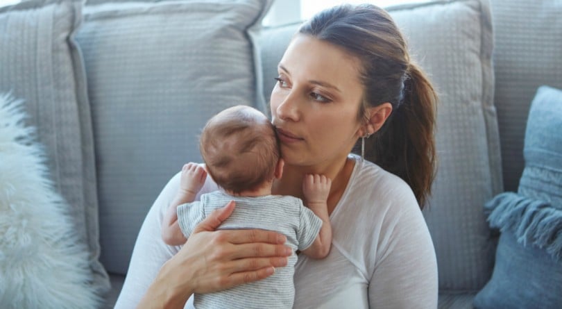 Mom holds baby on the couch, contemplating whether or not she should be giving up on breastfeeding