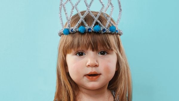 A little girl wearing a crown made of silver pipe cleaners