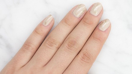 a hand with a gold leaf manicure on it