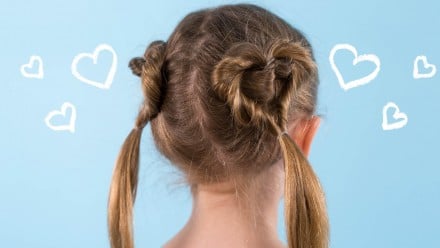 A blonde little girl with pigtails in the shape of hearts