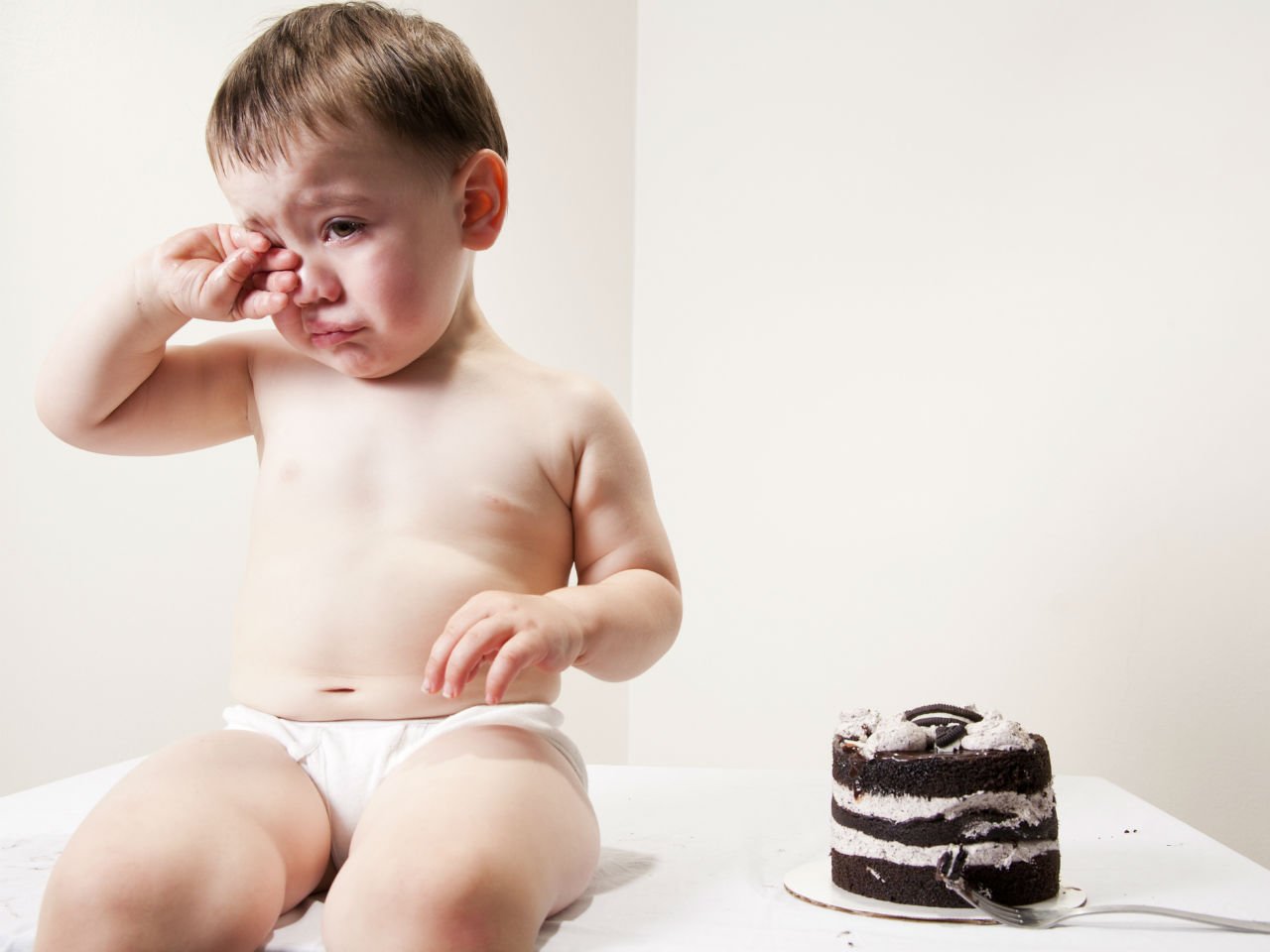 Baby crying next to a cake