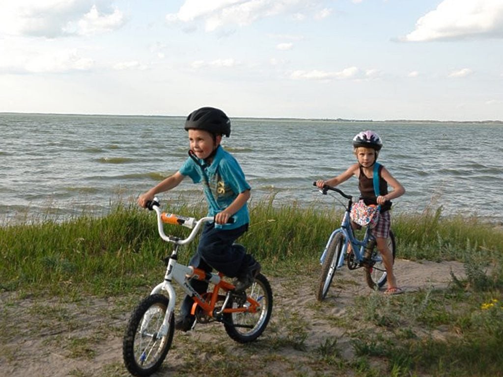 Two kids riding bikes on the sandy trails by Good Spirit Lake