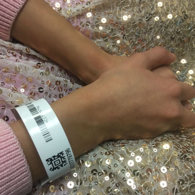 Nancy's daughter who has a chronic illness with her hands crossed over a sequin dress with a hospital bracelet on