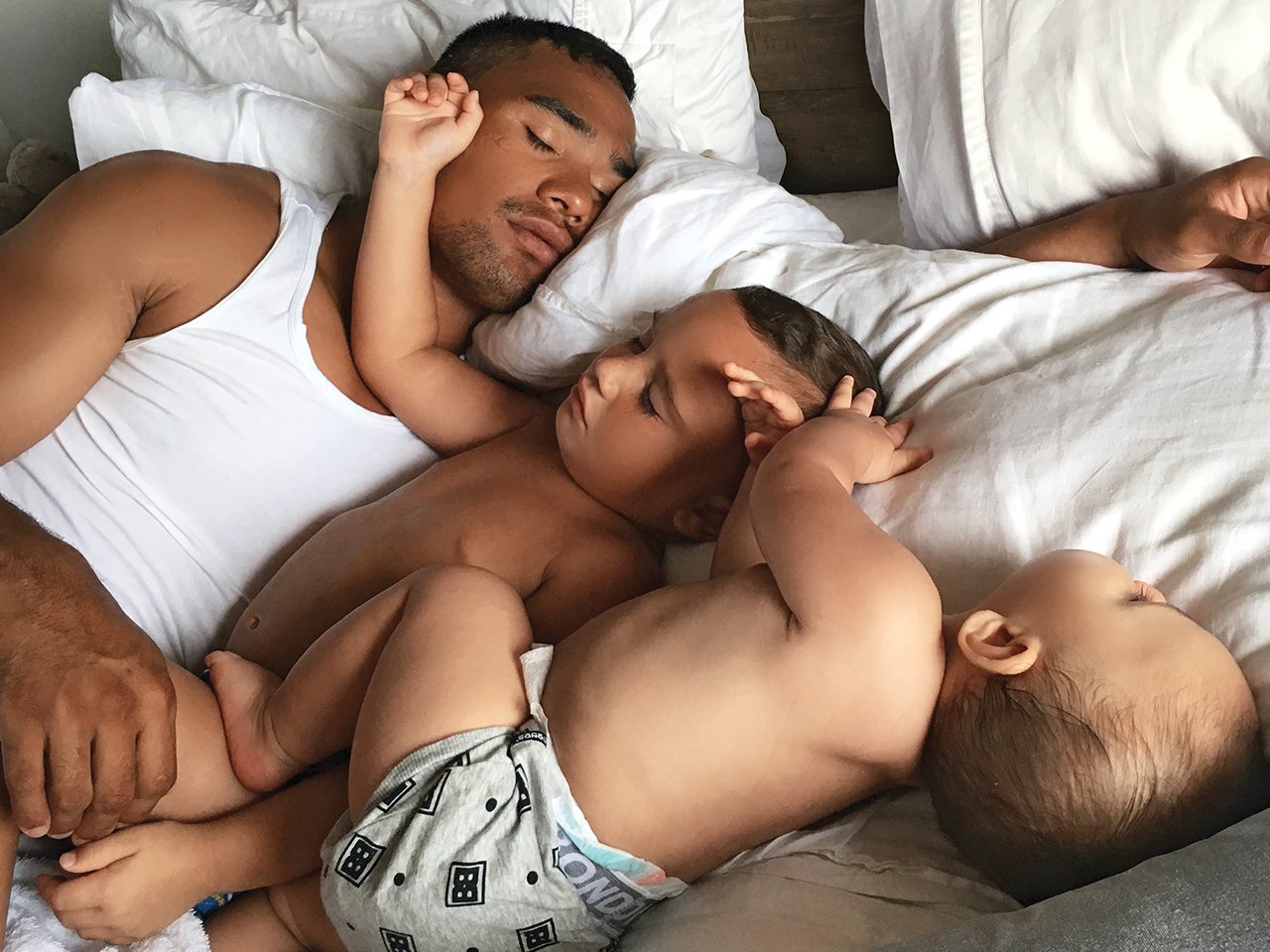 Dad lays in bed sleeping next to his two sons