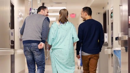 Ann, Tom and Pierre walking down the hospital hallway together