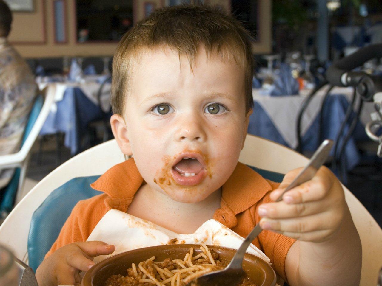 Young boy sitting in a fancy restaraunt eating a large bowl of spaghetti