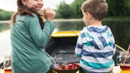 A little girl and boy eating in a canoe