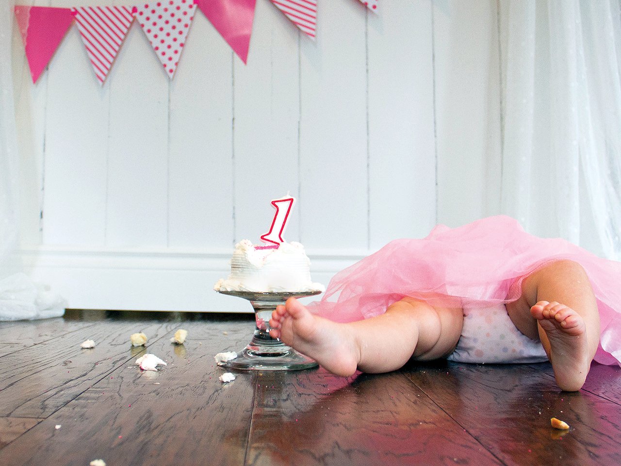 Baby lying beside a first birthday cake
