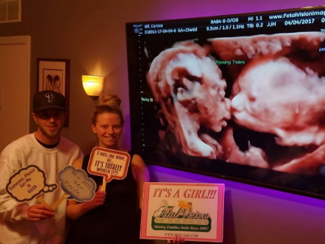 parents of twins kissing in womb standing in front of ultrasound