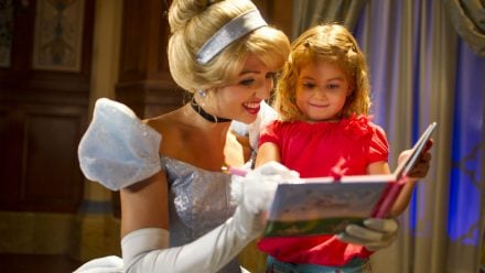 Cinderella signing an autograpgh book with a little girl at Walt Disney World