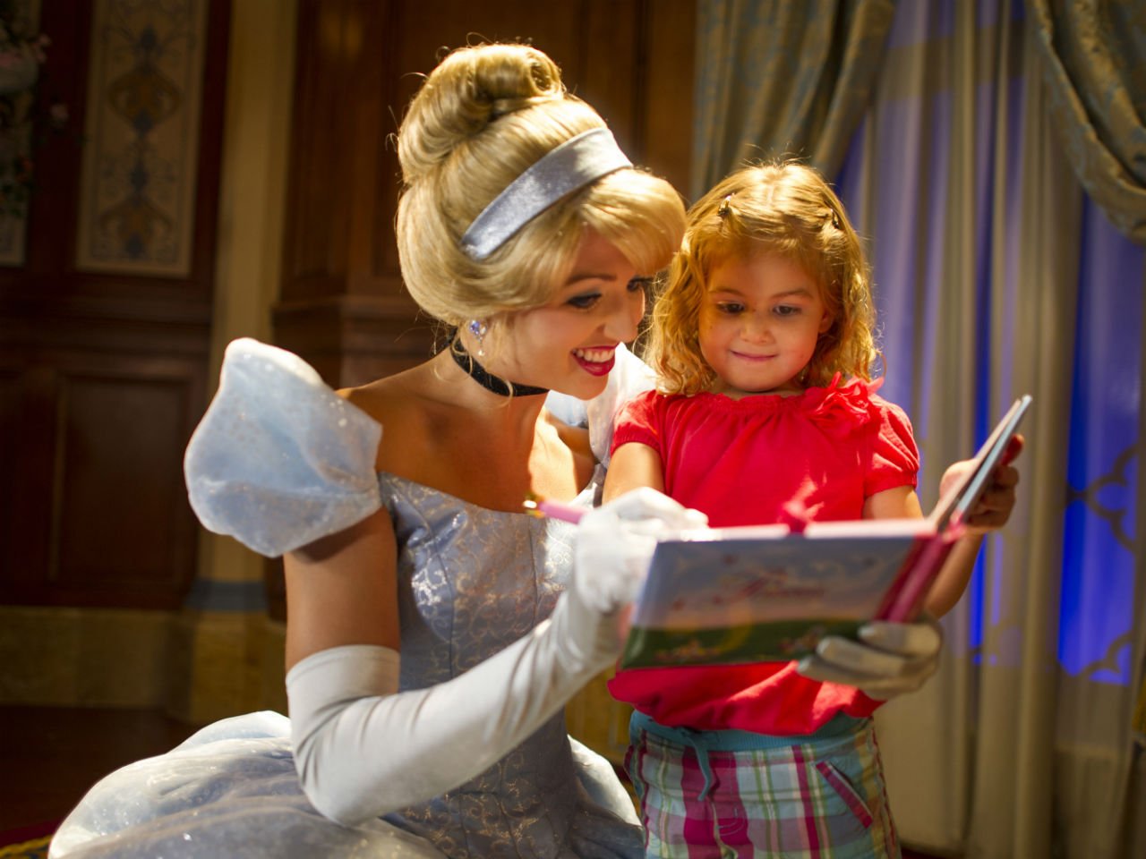 Cinderella signing an autograpgh book with a little girl at Walt Disney World 