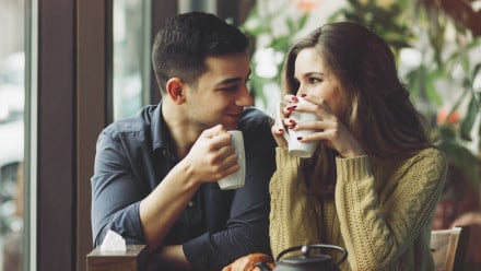 Couple drinking coffee and smiling at each other