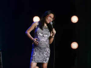 Ali Wong holding a microphone on stage