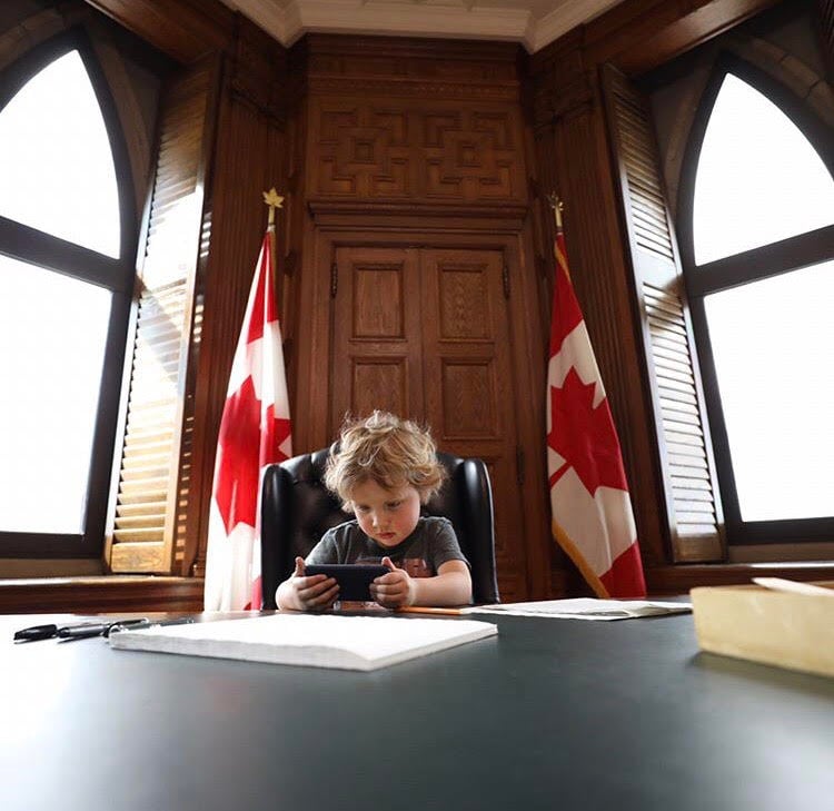Hadrien Trudeau at his dad's desk playing on a smartphone
