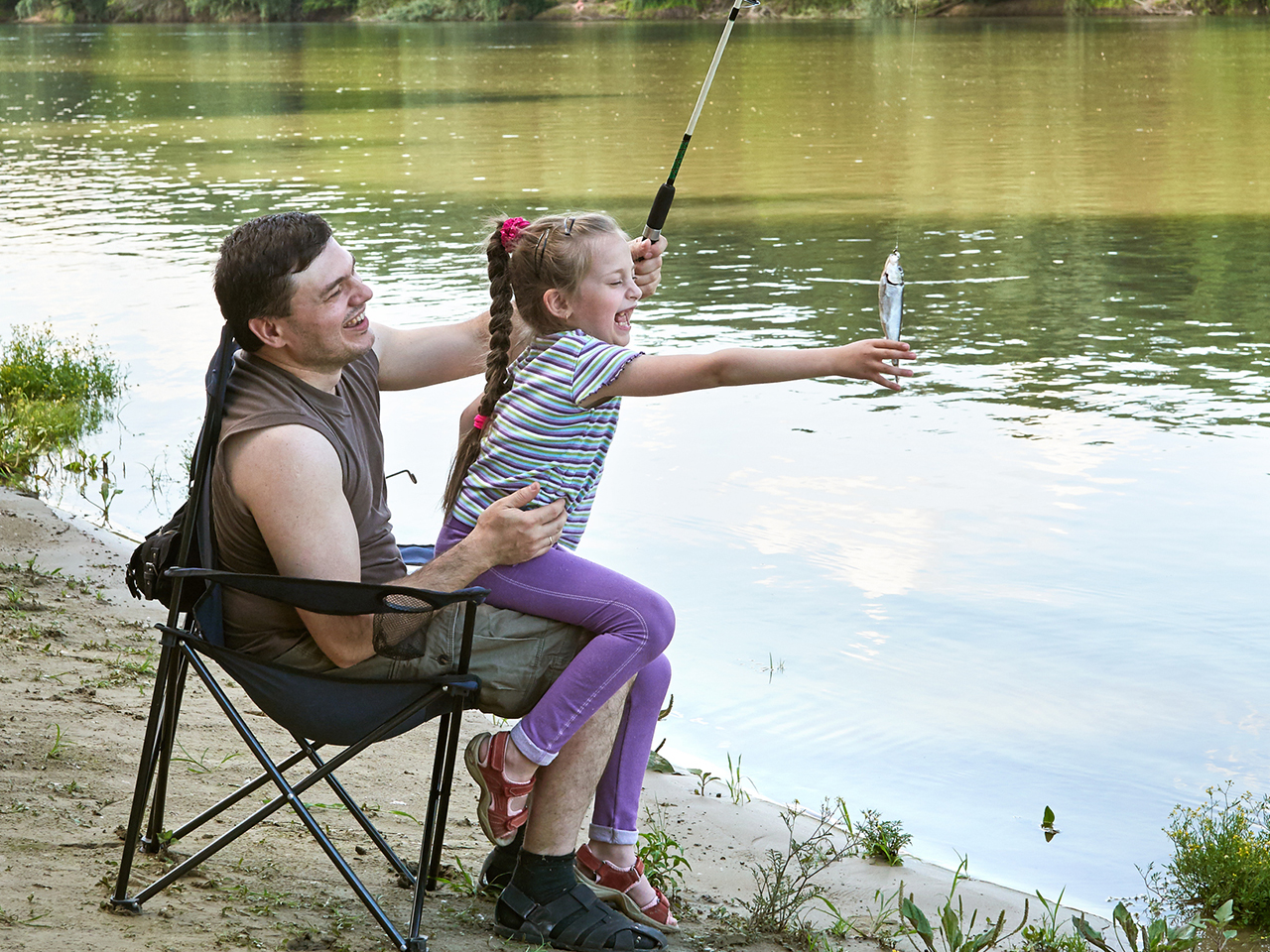 Dad and daughter laughing after catching a fish