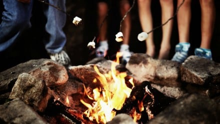 a family gathers to roast marshmellows and sing camp songs by the campfire