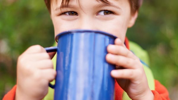 A little boy drinking from a blue mug