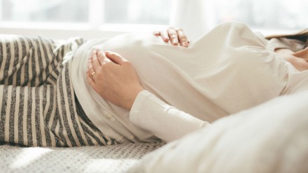 a woman lies in bed to rest while pregnant