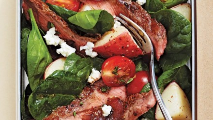 plate of steak, potatoes, tomatoes and cheese on spinach