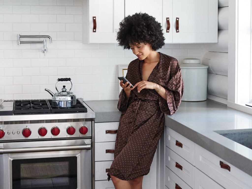 woman standing in kitchen on her phone