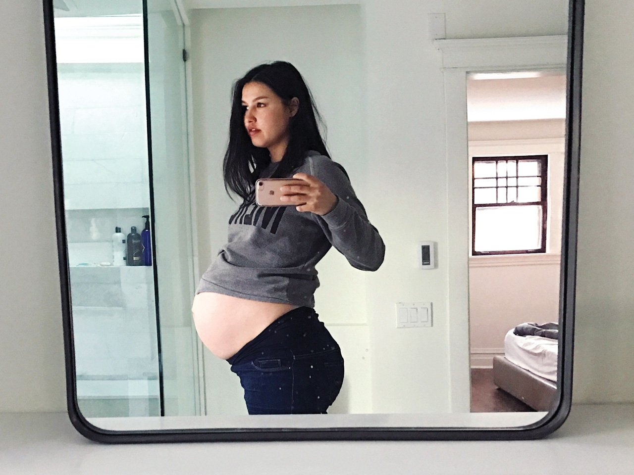 very pregnant woman takes selfie in bathroom mirror