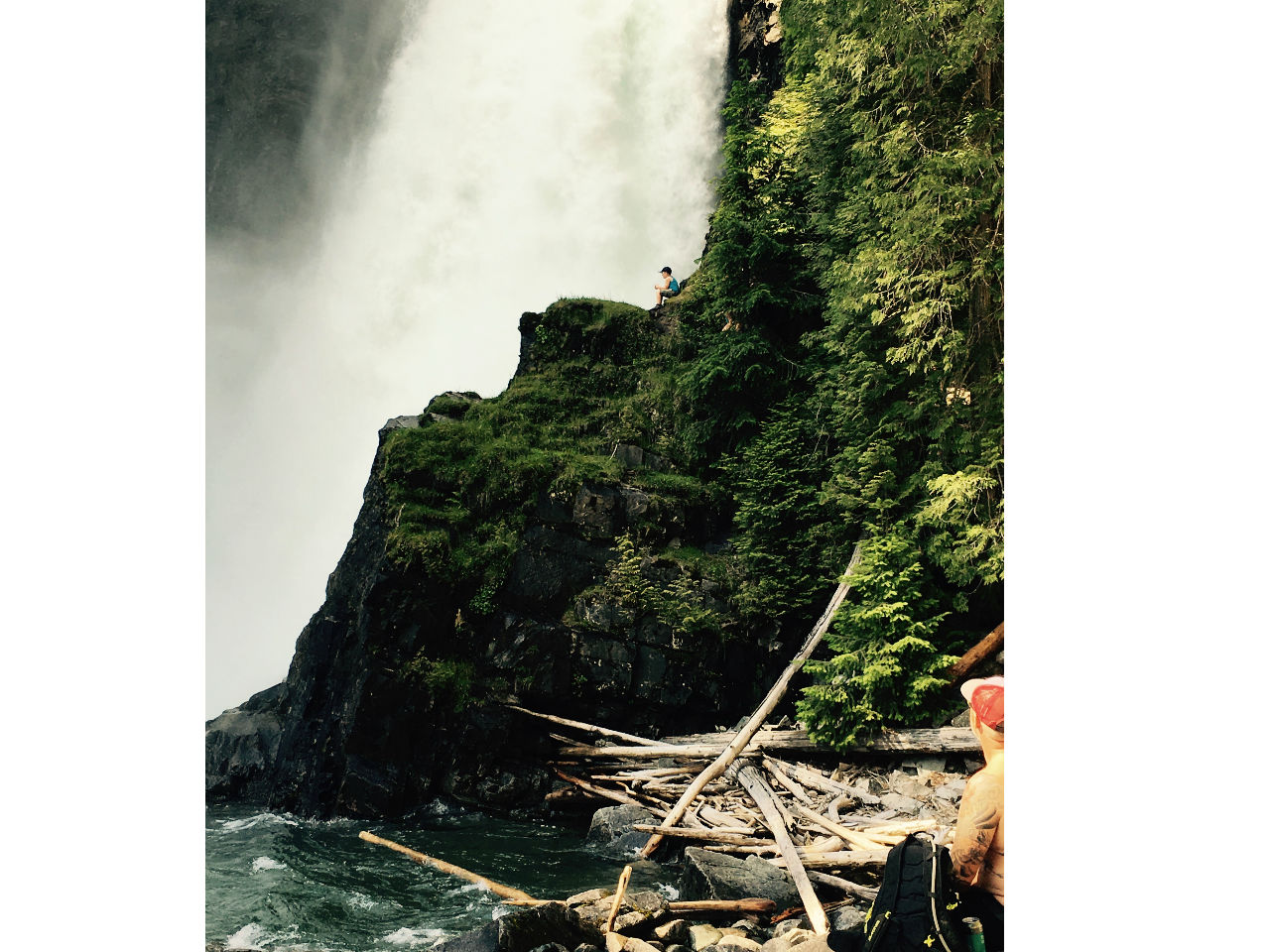 a little boy sitting by a waterfall