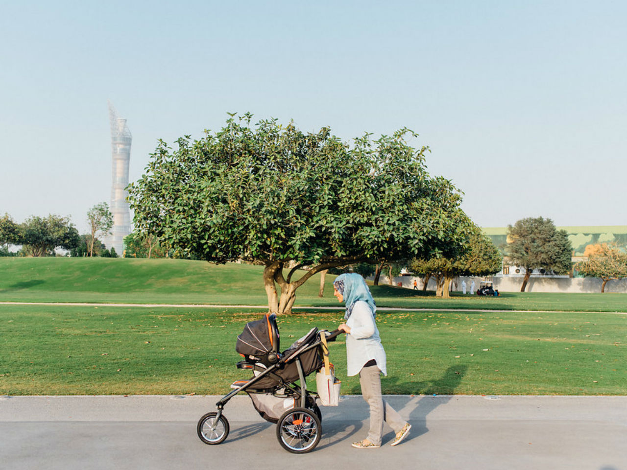 a mother walks her baby in a stroller at the park