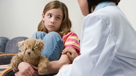 Young girl sitting in the hospital talking to a doctor