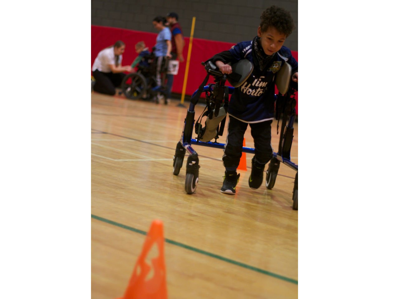 a young boy with cerebral palsy plays soccer in a gym 