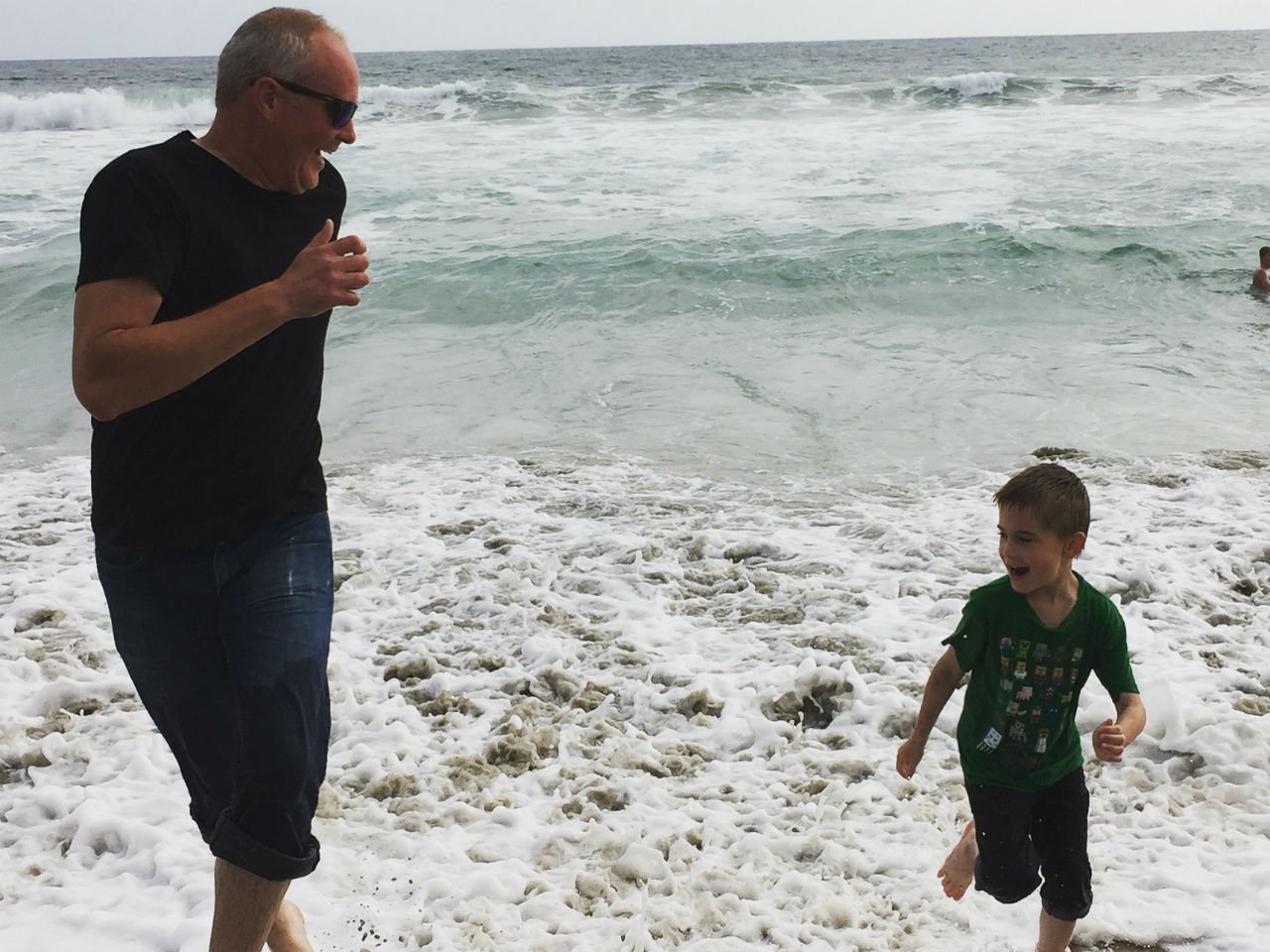 boy and father run on beach