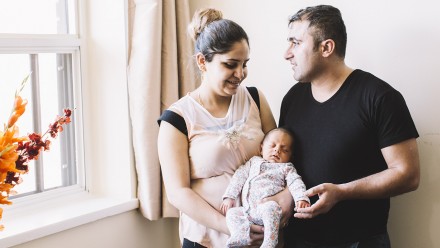 a mother and father, refugees from syrai, hold their new baby born in canada