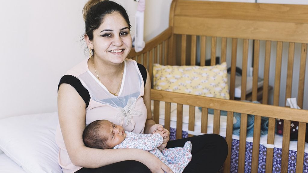 a new mother from syria holds her new baby born in canada