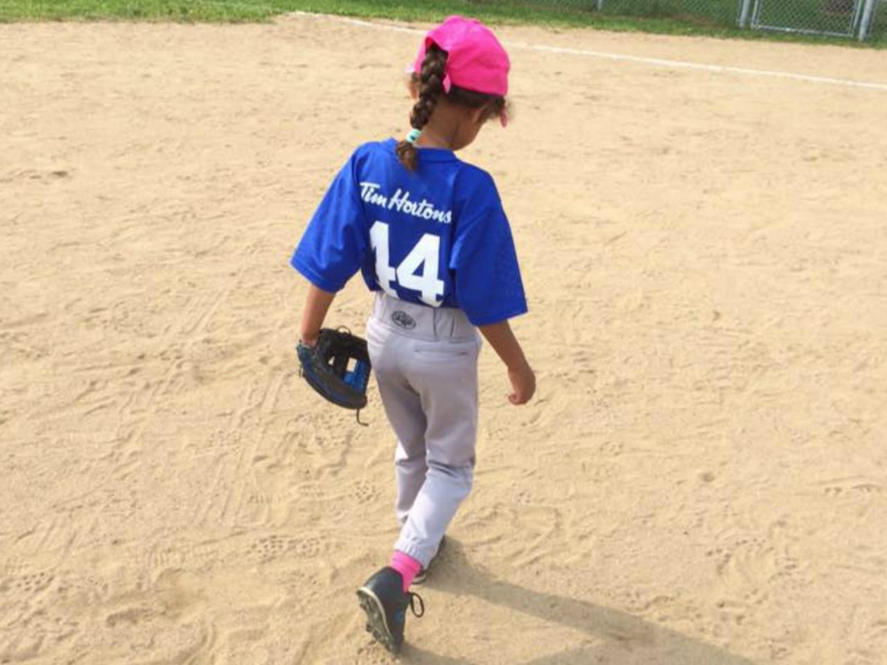 a little girl is playing baseball