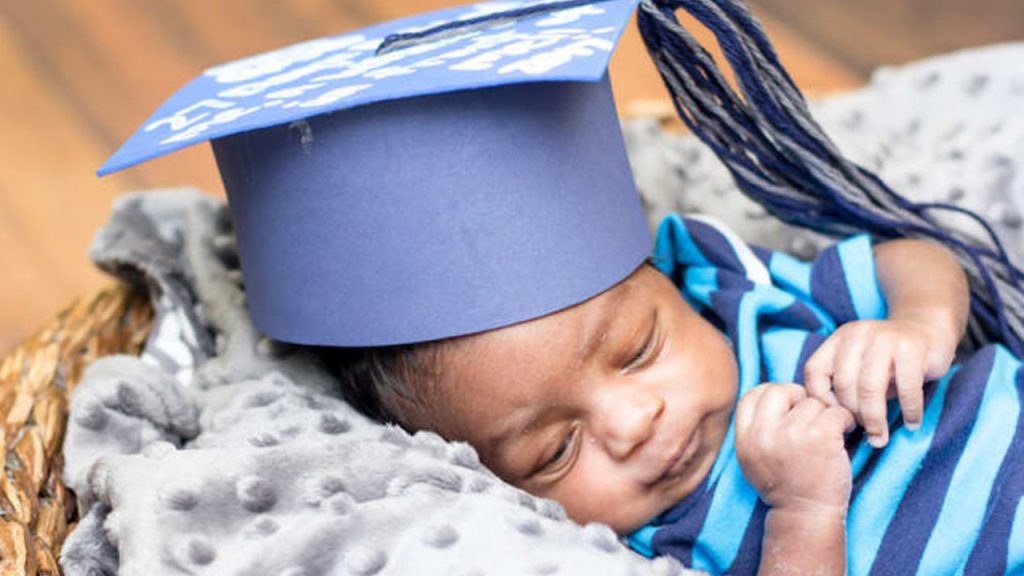 baby wearing a graduation cap in a basket