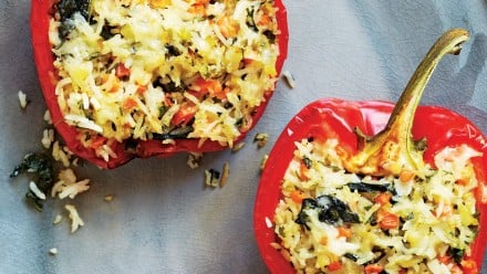 plate with three roasted red peppers stuffed with rice, veggies and melted cheese