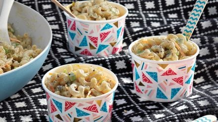 three dixie cups filled with macaroni salad on a picnic blanket
